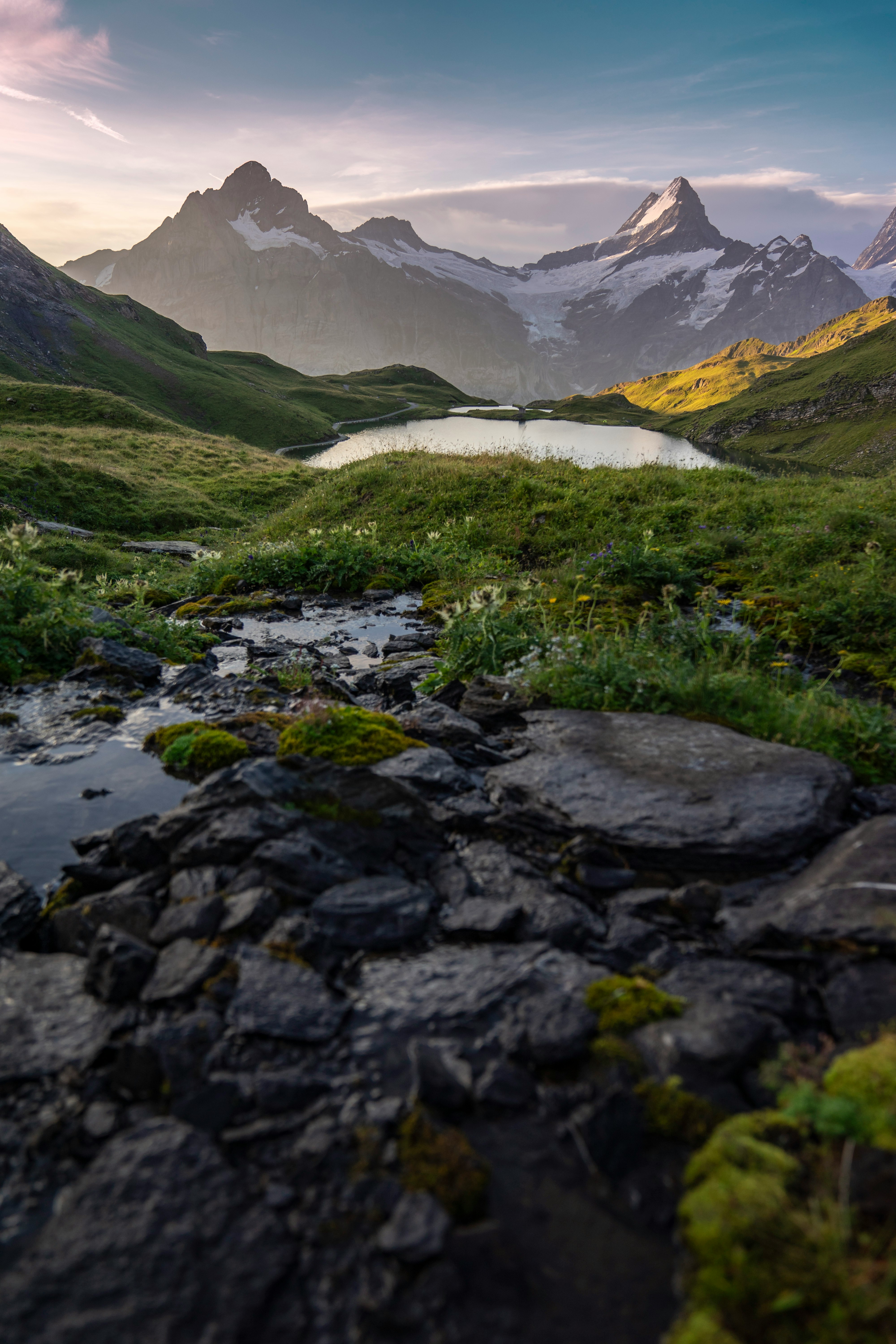 green grass and gray rocky mountain near lake during daytime